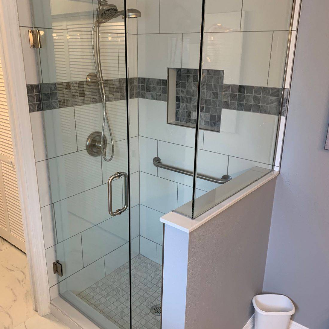 Glass corner shower with marble tile and a niche